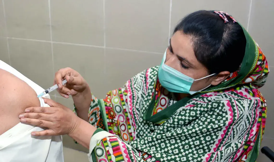 A health worker in PPE gives someone a vaccine.