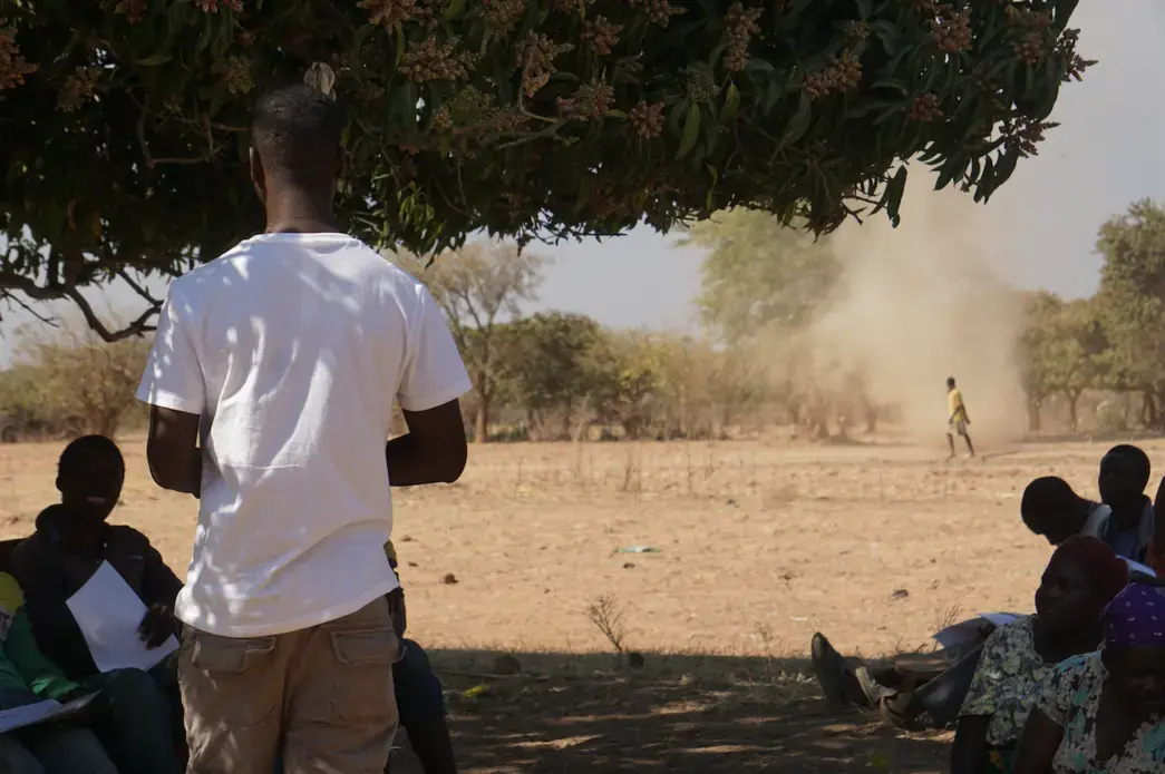 A whirlwind of sand spins past farmers