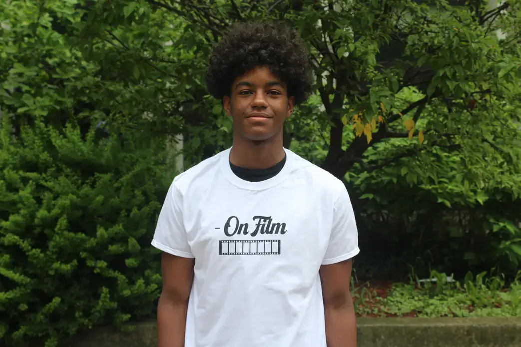 Jamar Jackson stands and smiles in a white tee shirt with trees and greenery in the background.