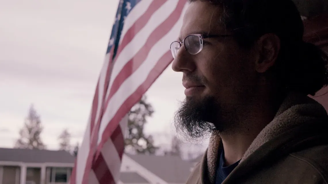 Man standing in front of flag