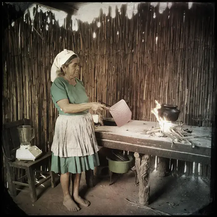 In San Lorenzo el Cubo, Guatemala, Albertina Pamal cooks on a raised concrete slab. Though the slab allows her to stand while she works, she still has to inhale the smoke from the open fire. Photo by Lynn Johnson. Guatemala, 2017.