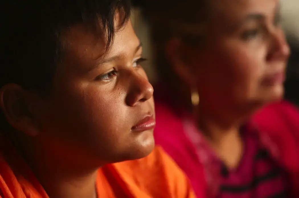 Daysi works ironing clothes at a laundry in Tijuana and her son, Jimmy, 12, sells shrimp at the beach near the U.S. border. Image by Erika Schultz. Mexico, 2019.