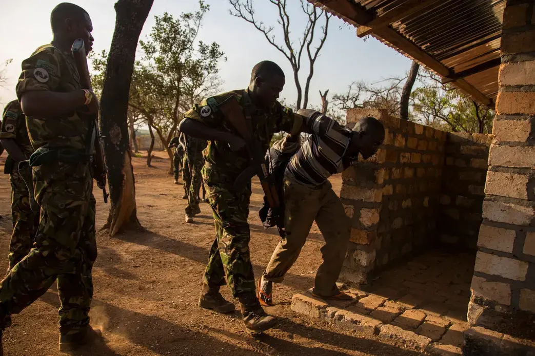 Rangers frogmarch suspected poachers to a holding cell at the park’s main base. Three days later, Chinko’s management will be left with no choice but to pay for a helicopter that will take the group to the capital and transfer them into CAR’s justice system. Image by Jack Losh. Central African Republic, 2018.