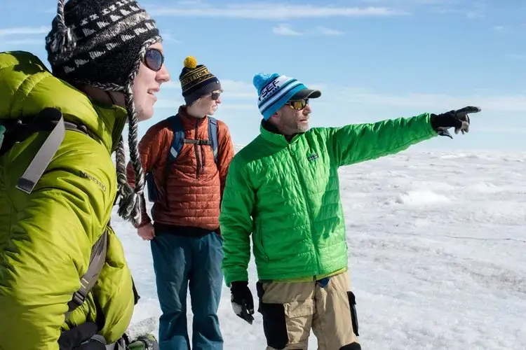 Graduate student Ian MacDowell, undergrad Aidan Stansberry, and principal investigator Joel Harper at work on the Greenland ice sheet. Image by Amy Martin. Greenland, 2018. 
