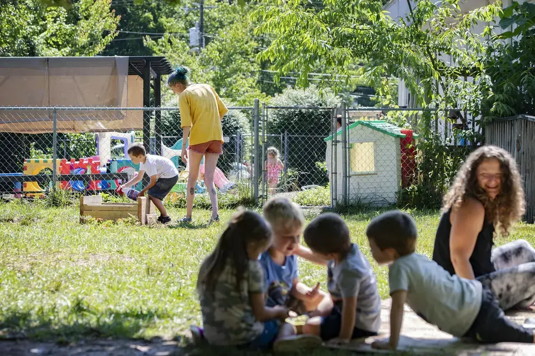 Bell’s School teacher Jodie Williams helps Oliver Fink, 5, spray rabbit repellent on vegetables growing in a raised bed garden as other children play on a blanket in the shade at the preschool in Fletcher on June 22, 2020. Image by Angeli Wright/Asheville Citizen Times/North Carolina News Collaborative. United States, 2020.