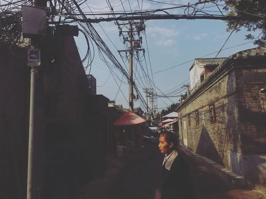 A woman walks through one of Beijing's hutong neighborhoods on Wednesday, Sept. 27, 2017, in Beijing, China. Hutongs are neighborhoods made up of narrow streets and alleys commonly found in Beijing. Image by Kelsey Kremer. China, 2017.