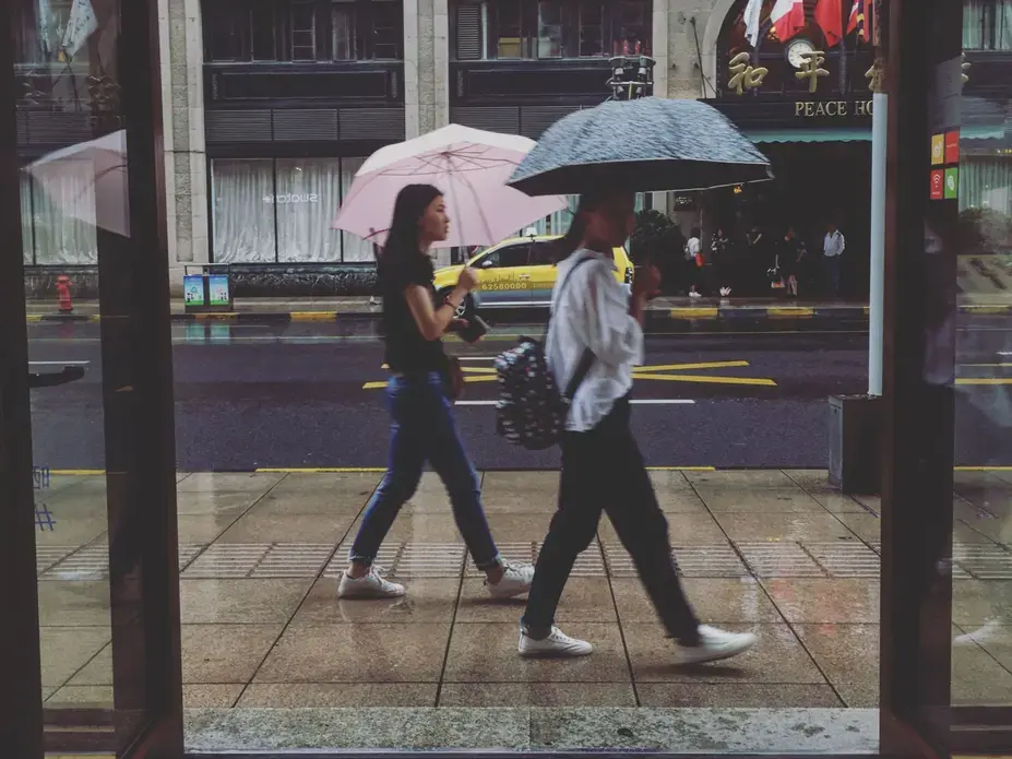 Shoppers take cover under umbrellas in a Shanghai shopping area during an afternoon rain storm on Sunday, Sept. 30, 2017. Image by Kelsey Kremer. China, 2017.