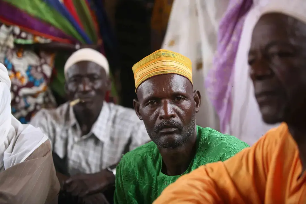 A resident of the village of Adouna, Niger, sits in a meeting with other villagers. Residents say Lutheran World Relief’s project to rebuild a dam near the village will increase usable farmland near the village and provide villagers with a way to get to market, thus increasing incomes.
