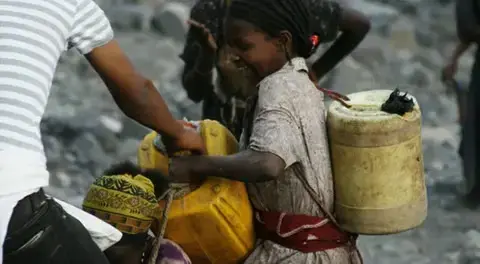 A girl carries cans of water. Image by Alex Stonehill. Ethiopia, 2008.