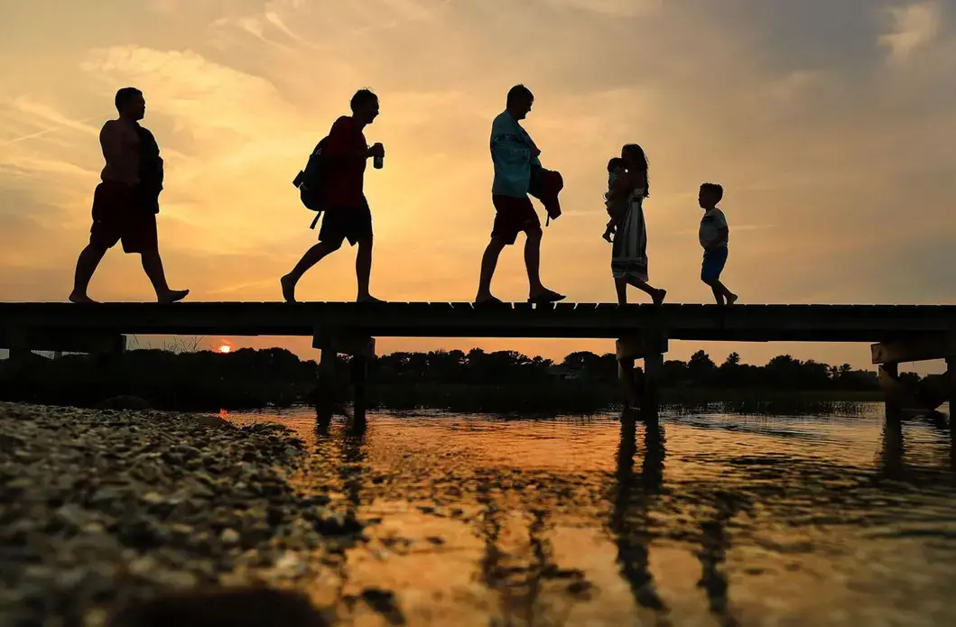 People walked along the iconic Sandwich Boardwalk as the sun sets. Image by John Tlumacki. United States, 2019.