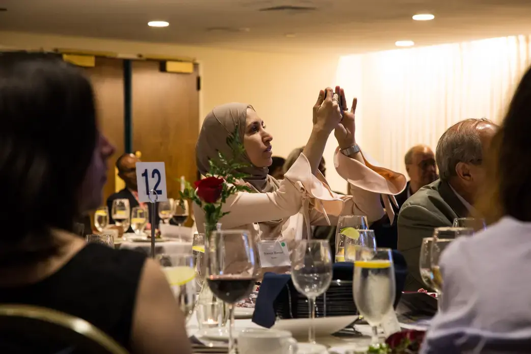 Sawsan Morrar, 2017 UC Berkeley Graduate School of Journalism fellow, photographs during the evening remarks. Image by Lorraine Ustaris. Washington, D.C., 2018. 