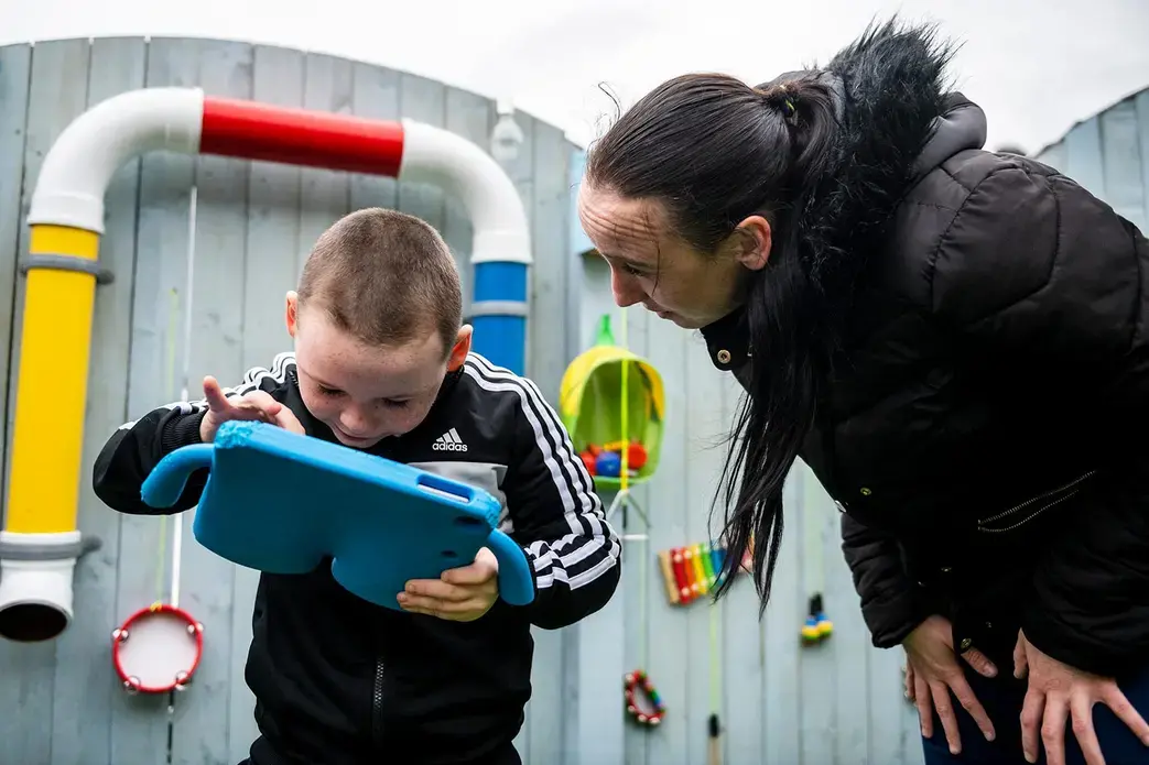 David plays on his iPad as his mother Leanne attempts to get his attention. Image by Michael Santiago. United Kingdom, 2019.