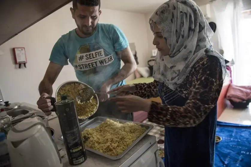 Noor Al Talaa, 22, and her husband, Yousuf Arsan, 27, prepare lunch at home with baby Rahaf, almost 6 months, at an apartment in Sidros, outside of Thessaloniki, Greece. Image by Lynsey Addario. Greece, 2017.