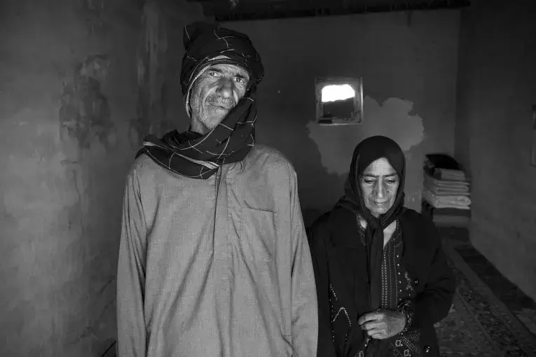 A fisherman and his wife live in Sistan, a small village on Hamoon Lake near the border with Afghanistan. After a devastating drought shrank the lake over the course of the last decade, the fisherman lost his job. Now, after each monthly sand storm, the village fills with sand. Their window which faces a small alley outside their home is still covered by sand. Image by Ako Salemi. Iran, 2016.