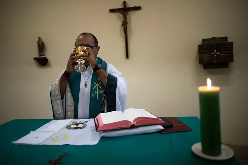 Father Amaro Lopes partakes in the sacrament while celebrating a mass in a chapel at the bishop’s house in Altamira. Image by Spenser Heaps. Brazil, 2019.