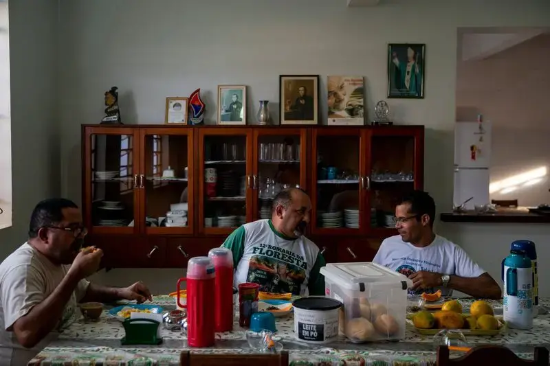 Father Amaro Lopes, center, eats breakfast with others at the bishop’s house in Altamira. Image by Spenser Heaps. Brazil, 2019.