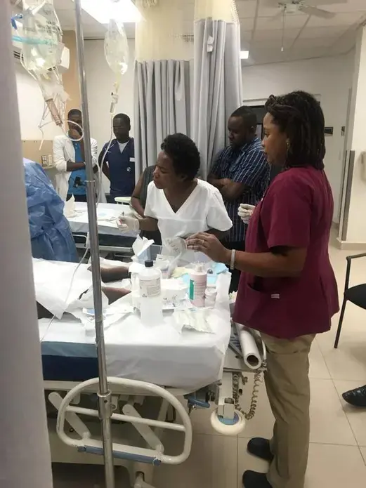 Staff members at the University Hospital of Mirebalais in central Haiti observe as pediatric oncologist Dr. Pascale Yola Gassant (not pictured), tends to Djooly Jeune, 18, who has Burkitt’s lymphoma. After his cancer failed to respond to an initial round of chemotherapy, Gassant began a new round on Tuesday, Dec. 18, at the teaching hospital. Image courtesy of Dr. Maxi Raymonville. Haiti, 2018.