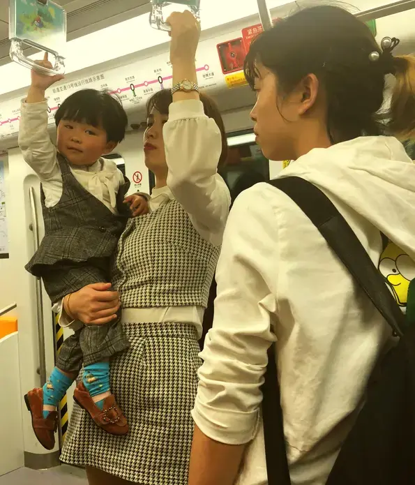 A young woman carrying her son on the train in Shanghai.&nbsp;Image by&nbsp;Argentina Maria-Vanderhorst. China, 2018.