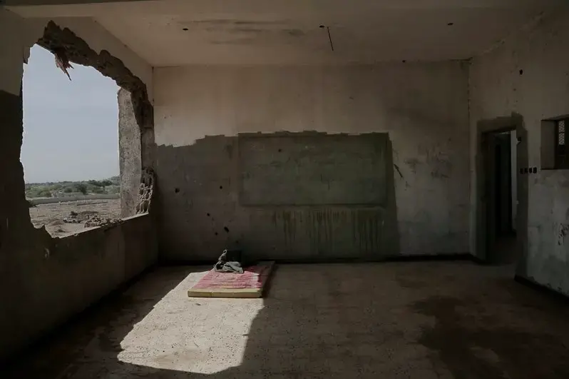 This Feb. 9, 2018, photo shows damage inside a classroom of a school that turned into a camp for displaced persons in Khanfar, Abyan, Yemen. Because of the country’s civil war, damaged buildings are hollowed-out versions of their former selves, a testament to past lives and aspirations of inhabitants who now scrape by on aid handouts and the bare minimum for survival. Image by Nariman El-Mofty. Yemen, 2018.</p>
<p>
