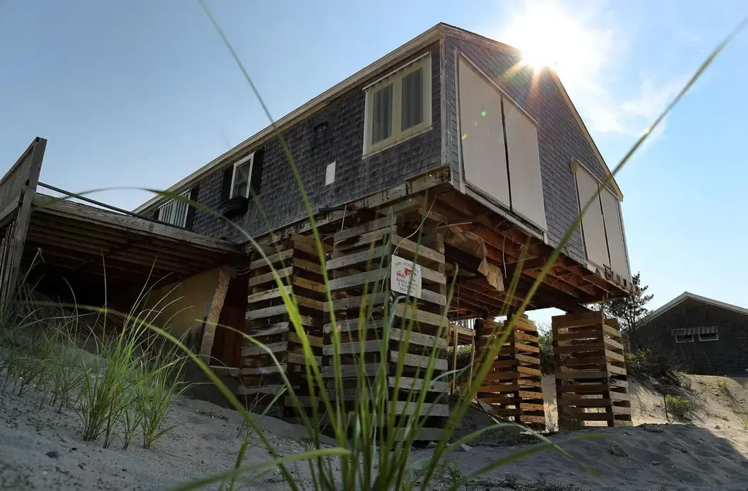 A storm-damaged, uninhabitable home sat on stilts on Salt Marsh Road on Spring Hill beach. Image by John Tlumacki. United States, 2019.