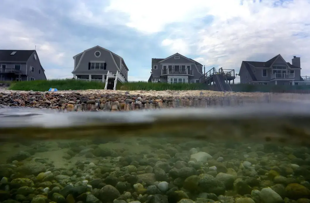 Erosion from the storms washed away much of the beach sand, leaving nothing but rocks along the coastline in Sandwich. Image by John Tlumacki. United States, 2019.