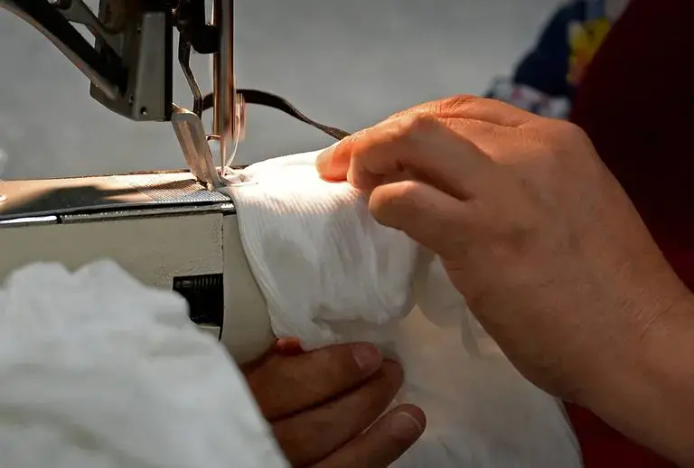 ASHEBORO, NORTH CAROLINA - Maria Reyes Alonso a sewer at the Bossong Medical plant in Asheboro, N.C. sews elastic bands onto masks on Thursday, July 16, 2020. Image by Jeff Siner/The Charlotte Observer/North Carolina News Collaborative. United States, 2020.