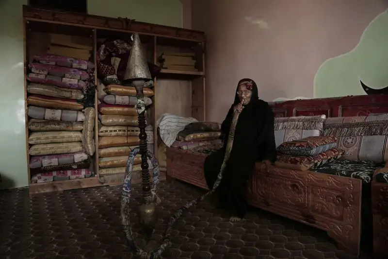 In this Feb. 12, 2018, photo, an elderly woman smokes a water pipe at the home of Ahmed al-Kawkabani, leader of the southern resistance unit in Hodeida, in al-Khoukha, Yemen. Image by Nariman El-Mofty. Yemen, 2018. </p>
<p>