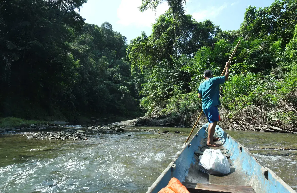 Man navigates his boat through a river in West Sumatra.