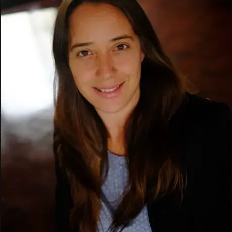 A woman wears a black jacket and blue blouse.