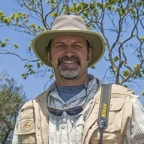Man with a hat and a mustache looks into the camera