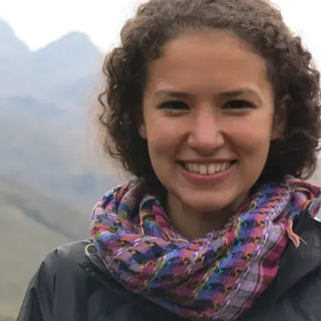 A woman with curly hair and a purple scarf stares in the camera