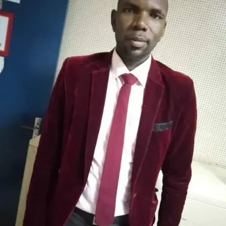 A man wearing a purple jacket and tie with a white work shirt.