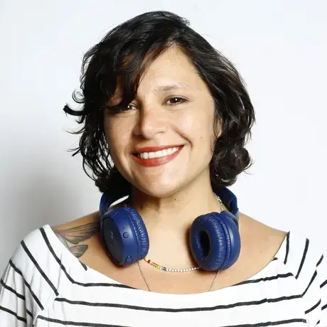 A woman with short hair, headphones, and wears a striped shirt.