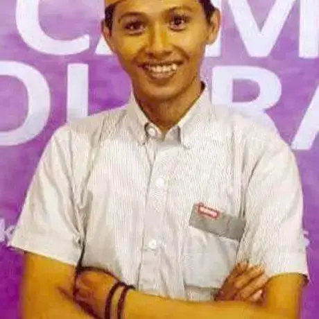 A man wears a grey shirt and an Indonesian, black songkok hat.
