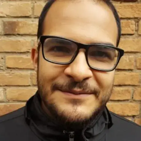 A man with glasses stares and smiles into the camera
