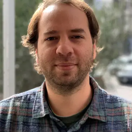 A man with facial hair and wears a striped shirt.