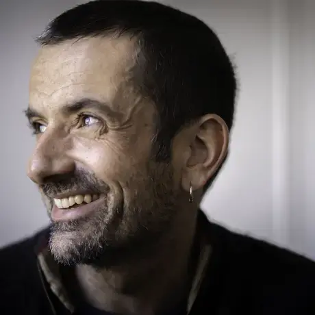 A profile headshot of a smiling man with short dark hair