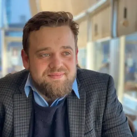 photo of a man with short hair and a beard in a blazer