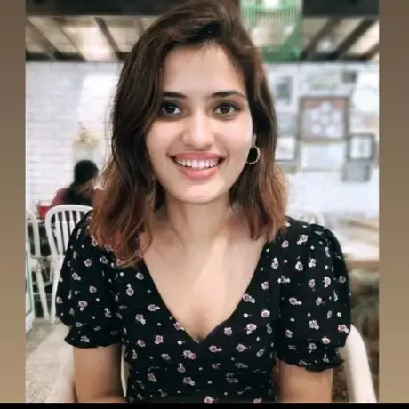 A woman with long dark hair wearing a black shirt smiles at the camera