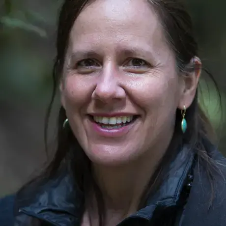 A woman with long dark hair wearing earrings and a jacket