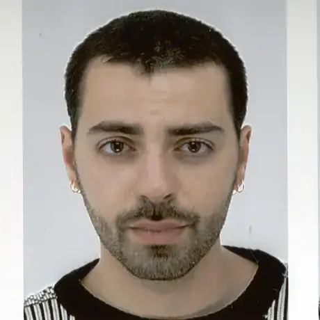 A man with short dark hair wearing a black and white shirt