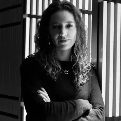 Black and white headshot of a woman with long curly hair with her arms folded