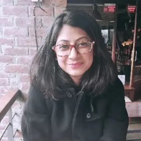 A woman with glasses and long dark hair wearing a black coat