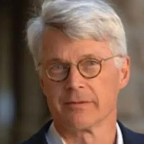 headshot of man in round glasses and suit