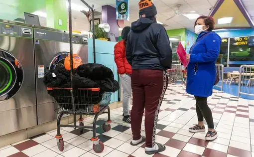 Margarita Sanchez, a promotora de salud — community health worker — with Centro San Bonifacia, conducts a survey about COVID-19 and helps answer questions for people on Jan. 15, 2021, at a laundromat in Belmont Cragin on Chicago's Northwest Side. Manuel Martinez / WBEZ News.