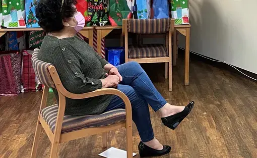 Mirna Cortez participates in a Zoom call in her building's community room, surrounded by holiday donations for seniors at the Retirement Housing Foundation. Image courtesy of Michelle Ornelas. United States, 2020.