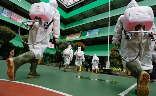 Volunteers from Indonesia's Red Cross prepare to spray disinfectant at a school closed amid the spread of coronavirus (COVID-19) in Jakarta. Image by REUTERS/Willy Kurniawan. Indonesia, 2020.