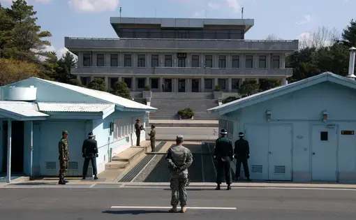 A view from South Korea towards North Korea in the Joint Security Area at Panmunjom. North and South Korean military personnel, as well as a single US soldier, are shown. Image by user: Driedprawns/Wikimedia Commons. South Korea, 2007.
