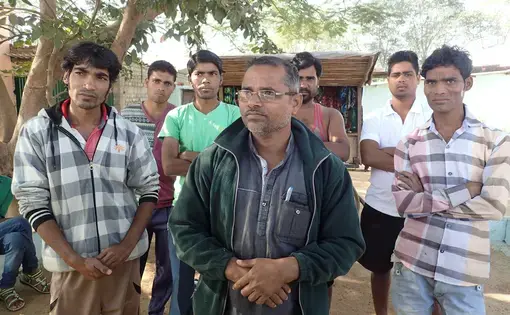 A group of high school and college students standing with a street vendor on the road outside Bade Seepat. Despite their education, they all said they expected to end up migrating to brick kilns like their parents. Image by Yardain Amron. India, 2017.