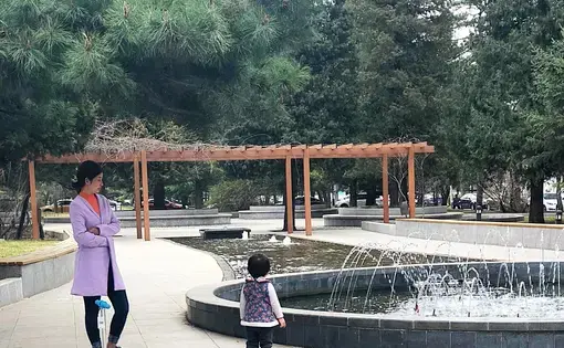 A young woman stands with her daughter in the park in front of Minzu University in Beijing. Image by Argentina Maria-Vanderhorst. China, 2018.